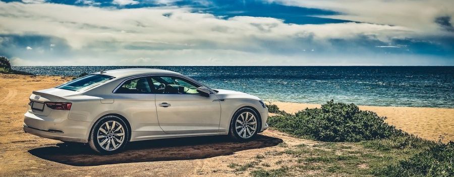 Auto steht am Strand mit Meer im Hintergrund