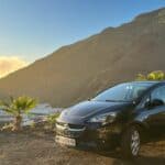 Opel Corsa Mietwagen auf Teneriffa vor einem Berg und Palmen mit blauem Himmel