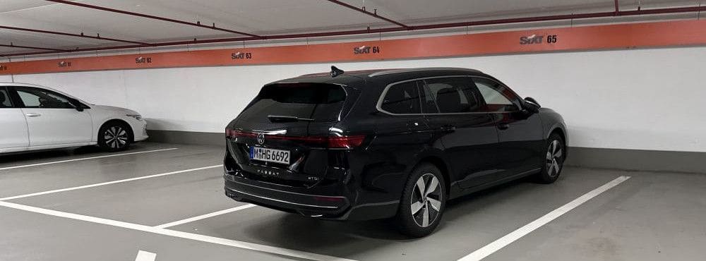 Ein schwarzer VW Passat Variant in einer Sixt-Tiefgarage, eingeparkt auf einem Stellplatz der Mietwagenkategorie IWAR.